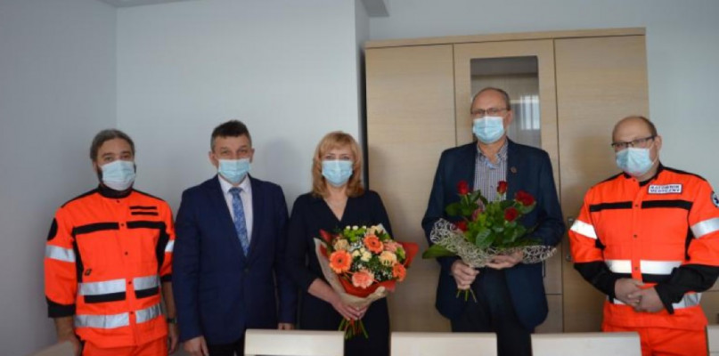Zdjęcie przedstawia pana Starostę Sanockiego Stanisława Chęcia wraz z Panią Baetą Pieszczoch Dyrektor Bieszczadzkiego Pogotowia Ratunkowego SP ZOZ w Sanoku wręczający kwiaty dla Pana Janusza Bukłada. Obok stoją ratownicy medyczni.